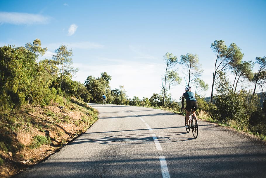 ciclista de camino rural, con curvas, rodeado, árboles, verde, carretera, paisaje, luz, montaña, escénico
