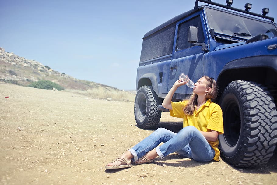 young, woman, wearing, half-sleeved, yellow, shirt, denim jeans drinking water, bottle, sitting, besides