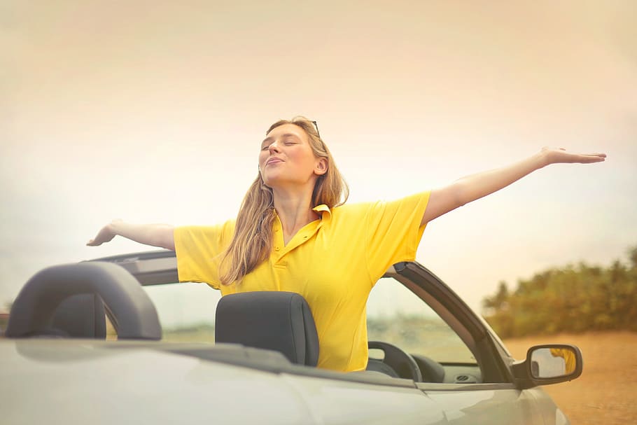 woman, yellow, shirt, enjoying, weather, open, arms, convertible, silver car, 25- 30 years