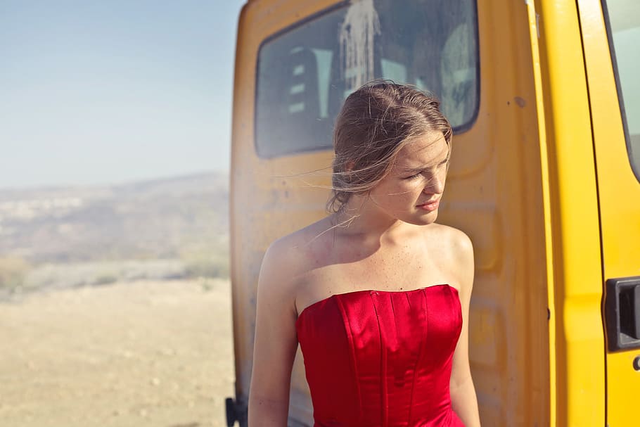 young, adult woman, red, party gown dress, standing, yellow, truck, outdoor, photoshoot, 20-25 years