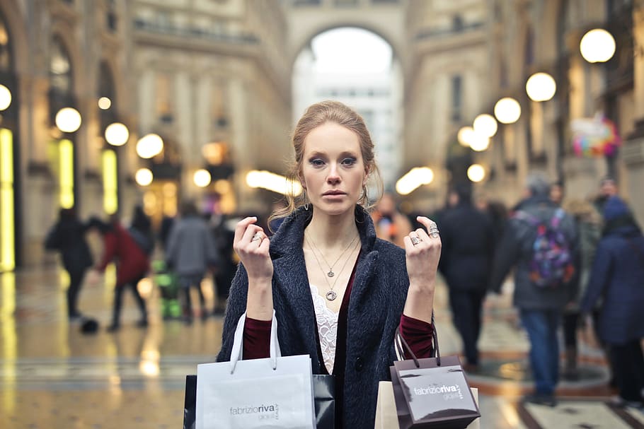 young, blonde, woman, wearing, overcoat, holding, shopping bags, hands, 25-30 year old, blonde hair