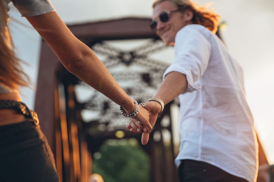 caucasian couple, holding, hand, sunset, 25 to 30 year old, bridge, outdoors, portrait, ring, trousers