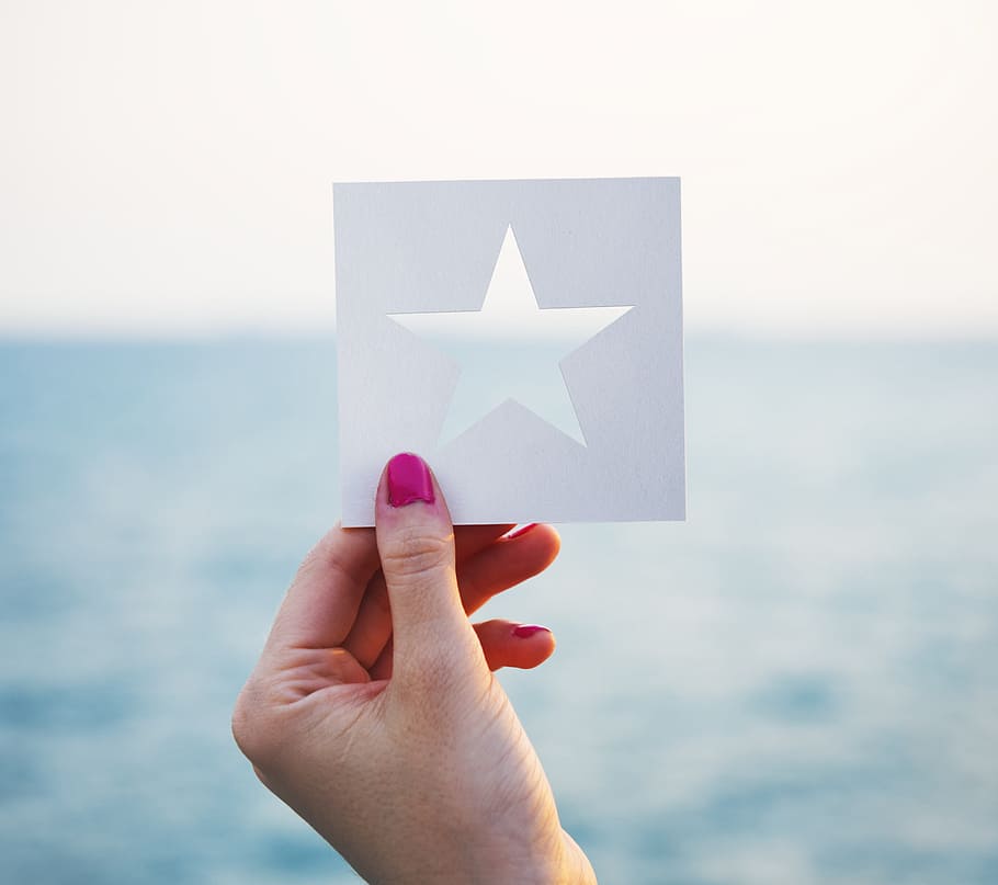female, hand, holding, star, shaped, paper, cut, template, ocean, background