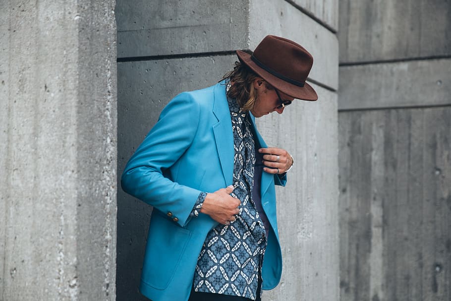 jovem, homem caucasiano, vestindo, turquesa, azul, jaqueta, marrom, chapéu, posando, ao ar livre