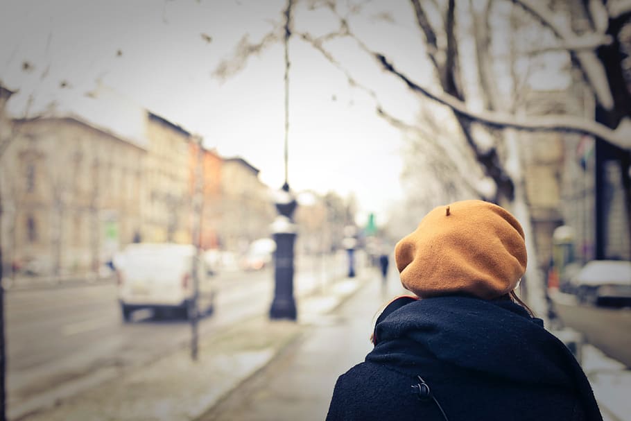 woman, wearing, orange, cap, walking, sidewalk, winter day, architecture, blue, blurred