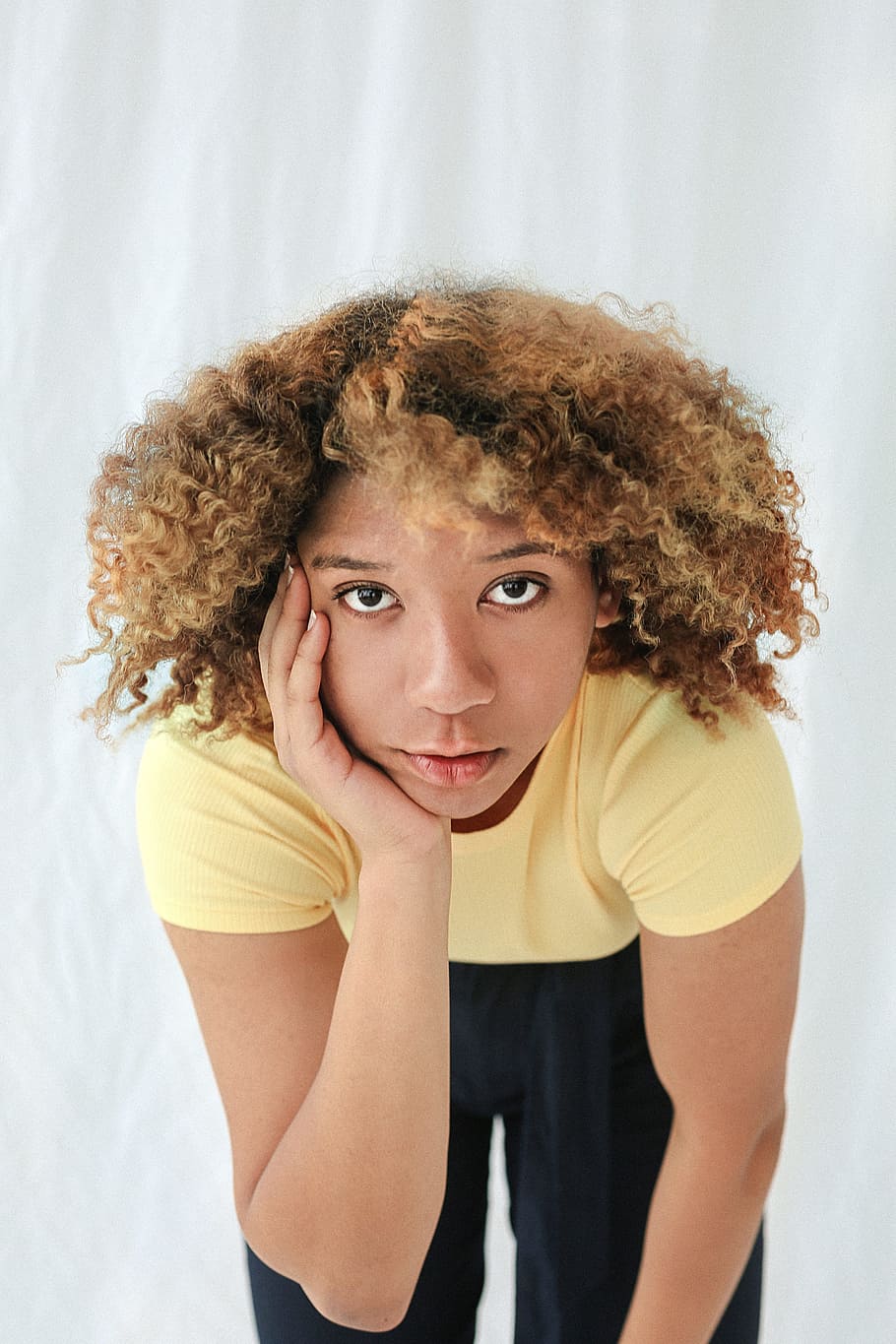 woman, hand, face, thought, think, yellow, t-shirt, curly, hair, black