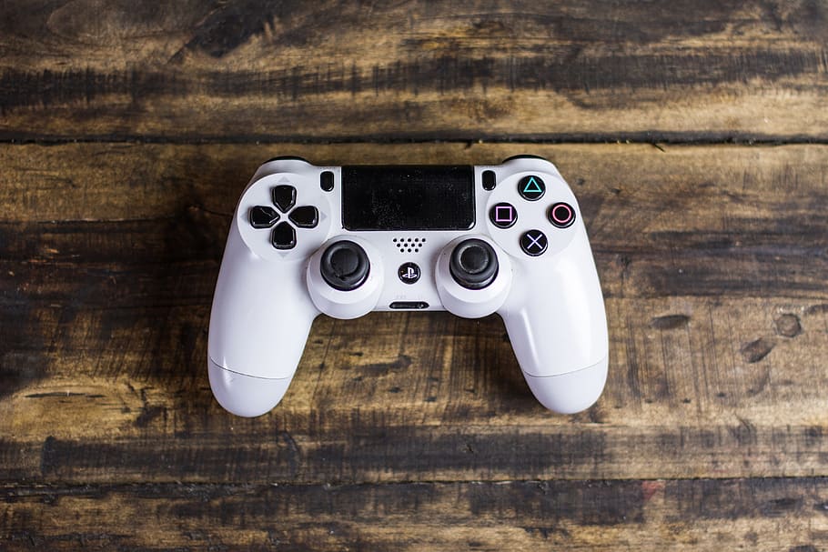 ps4 games controller, technology, gaming, wood - material, table, indoors, still life, white color, directly above, two objects