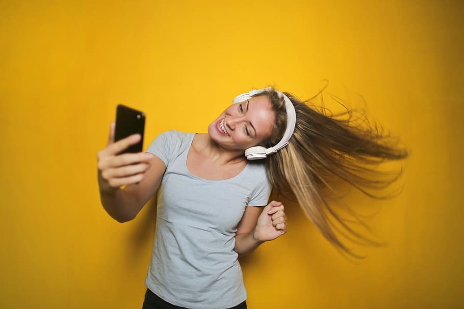 young, woman dancing, listening, music, wireless, headphones, connected, smart, phone, isolated