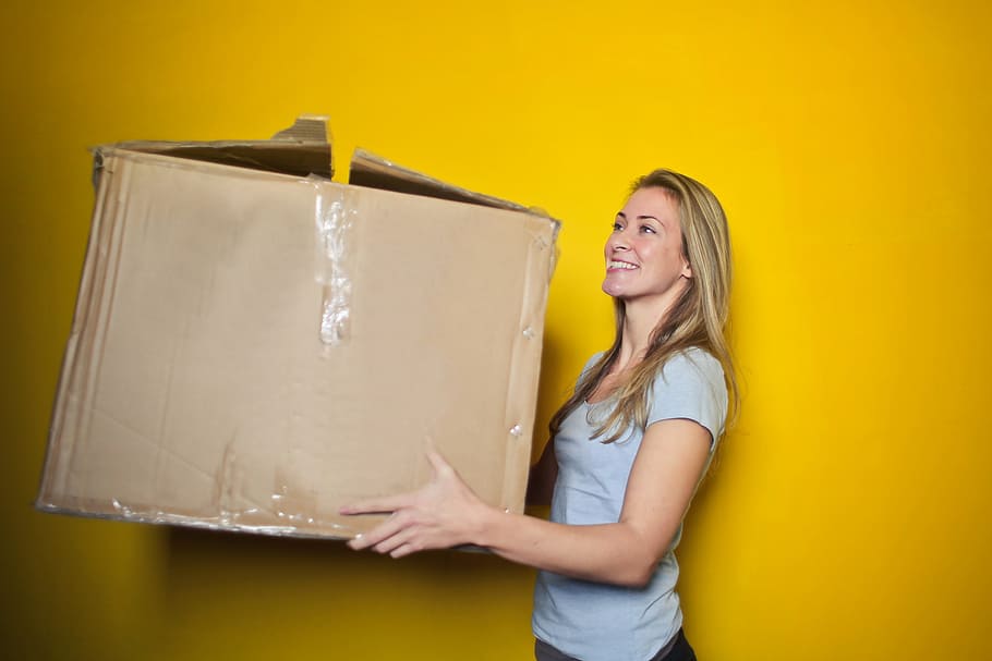 young, woman, holding, brown, cardboard box, yellow, wall, 25-30 Years, Box, Denim