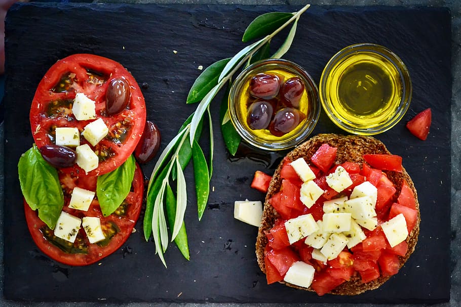 dakos, tomato, olives, olive oil, branch, leaves, plating, cheese, oregano, basil