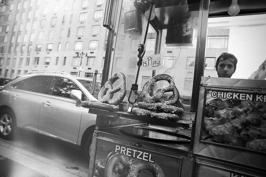 food stand, pretzels, chicken, street, display, man, bandana, car, mode of transportation, transportation
