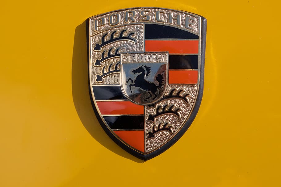 logo, porsche, emblem, metal, yellow, close-up, studio shot, yellow background, indoors, colored background