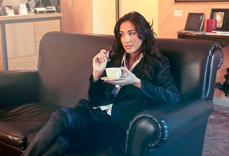 woman, black, blazer, holding, teacup, spoon, two, seater, sofa, 30-35 years