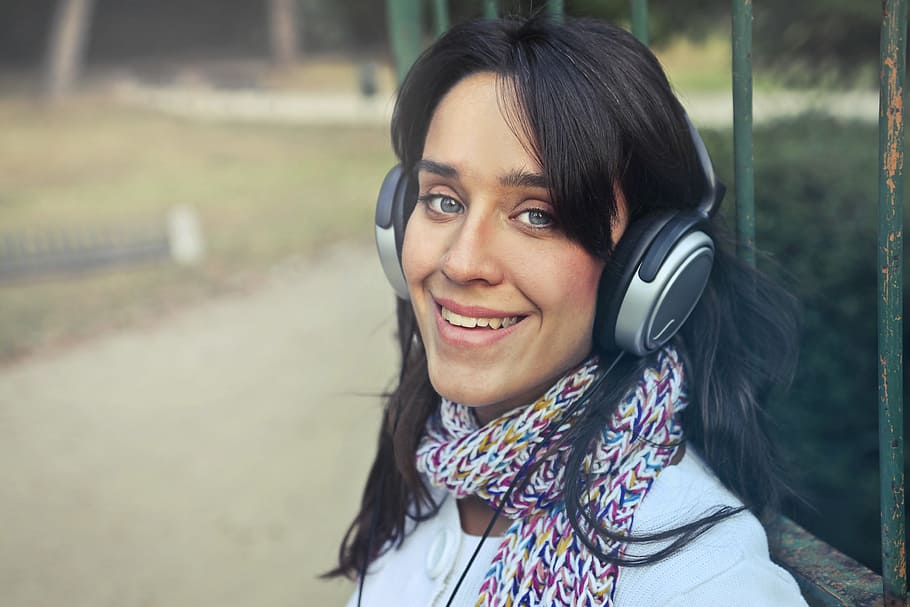 jovem, mulher, vestindo, cachecol, usando, fones de ouvido, ouvir, música, parque, 25-30 anos