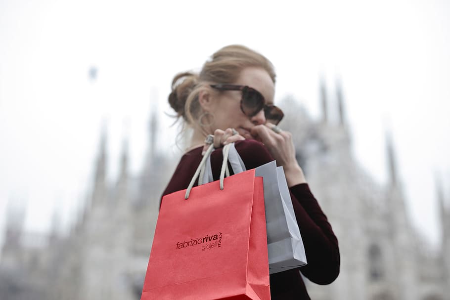 young, blonde, woman, wearing, red, dress, holding, shopping bags, hand, looks