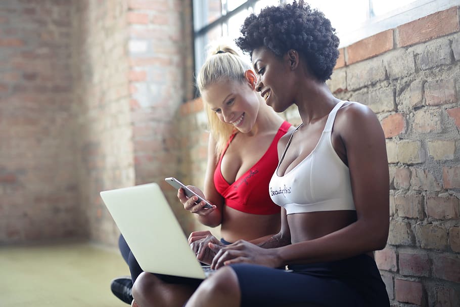 two, young, women, wearing, red, white, sports bras, using, laptop, mobile