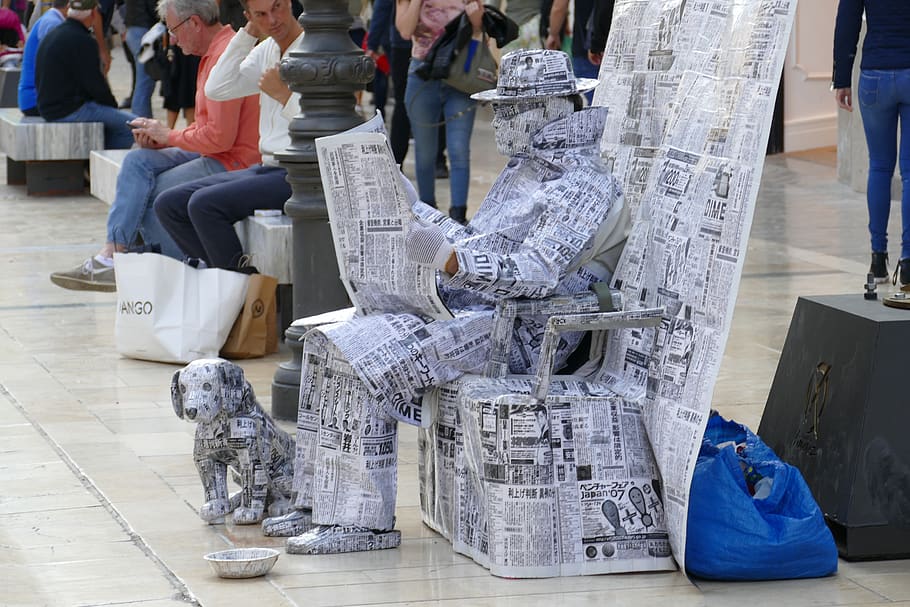 statue, alive, artist, street artist, newspaper, newsprint, dog, hat, glasses, covered