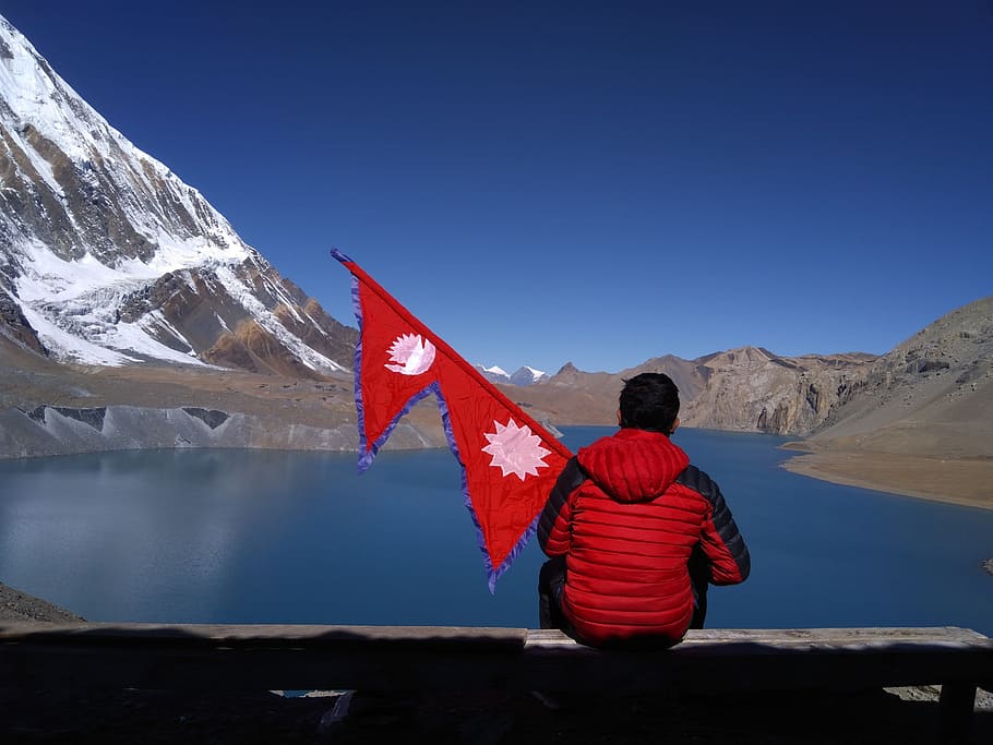 man, sitting, shore, tilicho lake, nepal, holding, flag., nature, himalayas, mountain