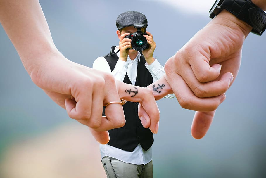 pareja, tenencia, manos, fotógrafo, toma, foto., coincidencia, tatuajes de dedos, tatuajes., amor