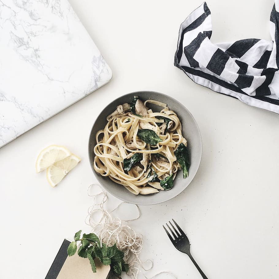 pasta, spinach, fresh, bowl, plate, fork, apron, chopping board, table, white